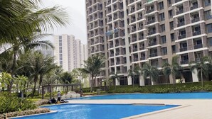 A residential building with a swimming pool surrounded by palm trees and greenery. - Sky House Bsd By Mizu Rooms (Pagedangan)