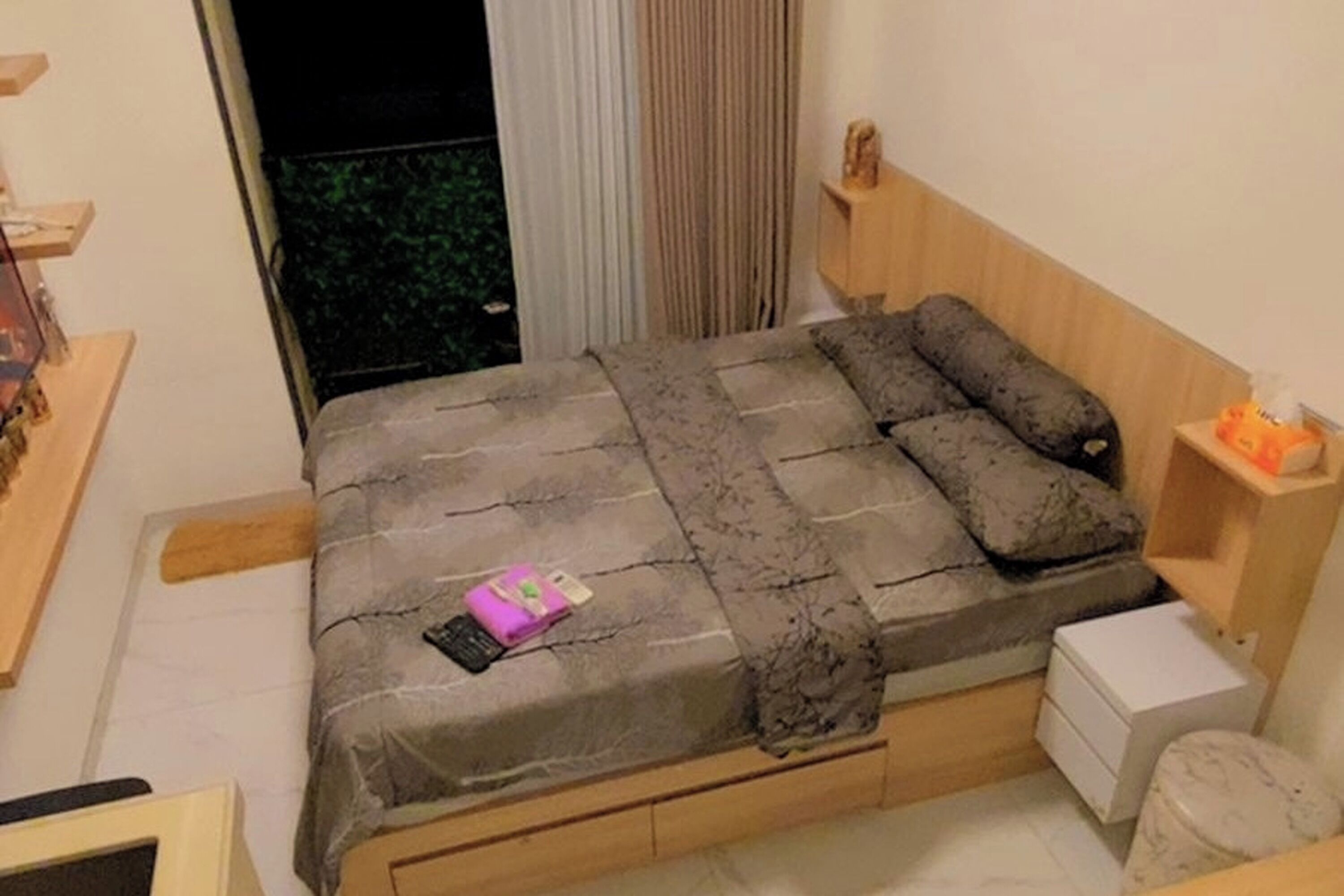 A bedroom with a bed, bedside table, and a small white cabinet.