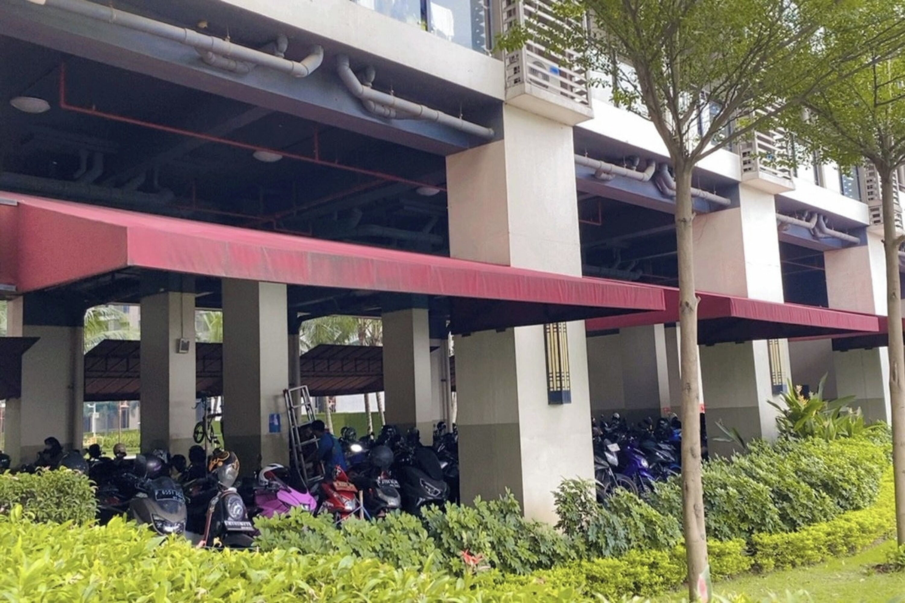 A covered parking area with multiple motorcycles parked underneath.
