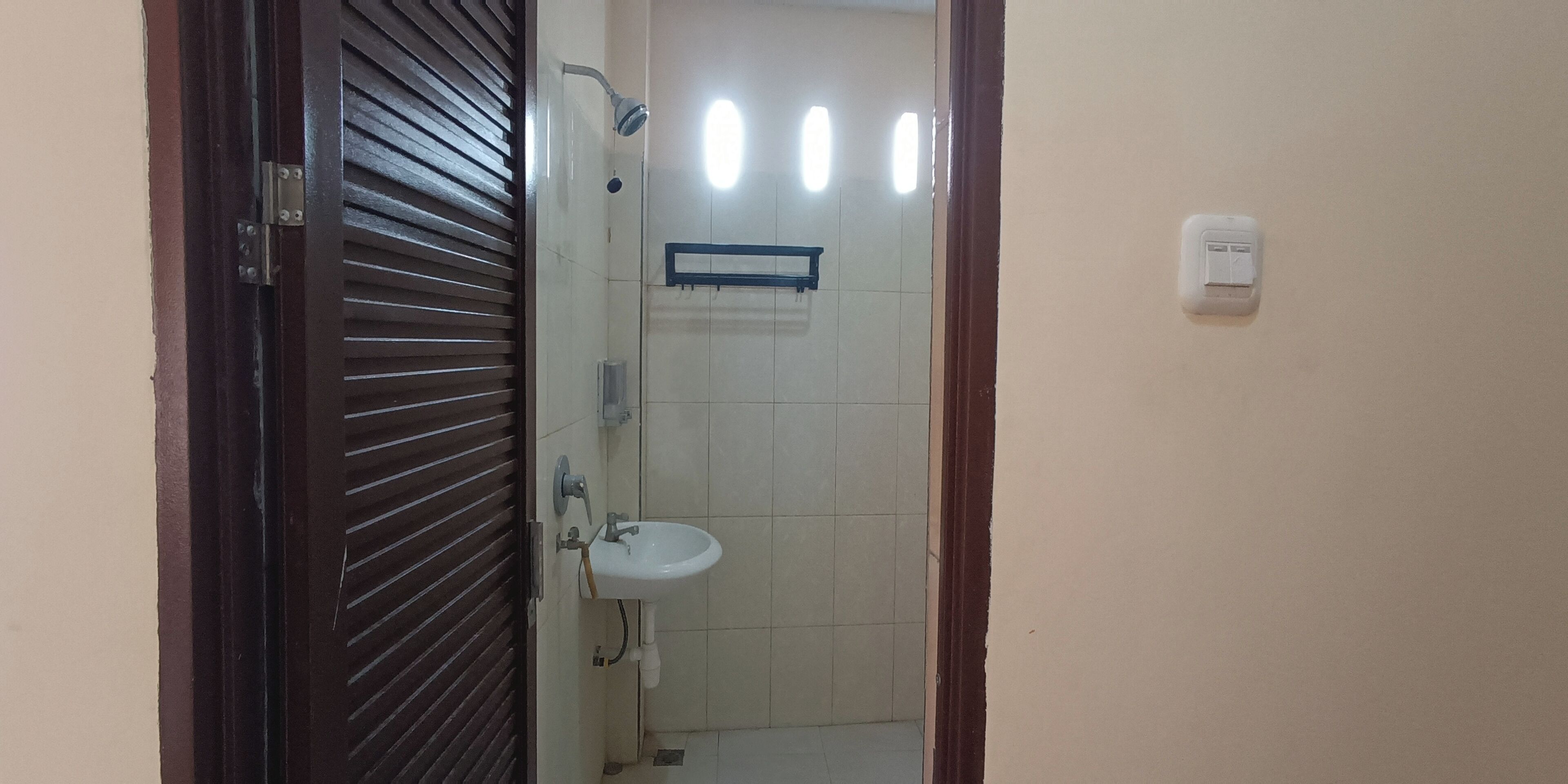 Une salle de bain avec un lavabo blanc, une douche et un porte-serviettes.