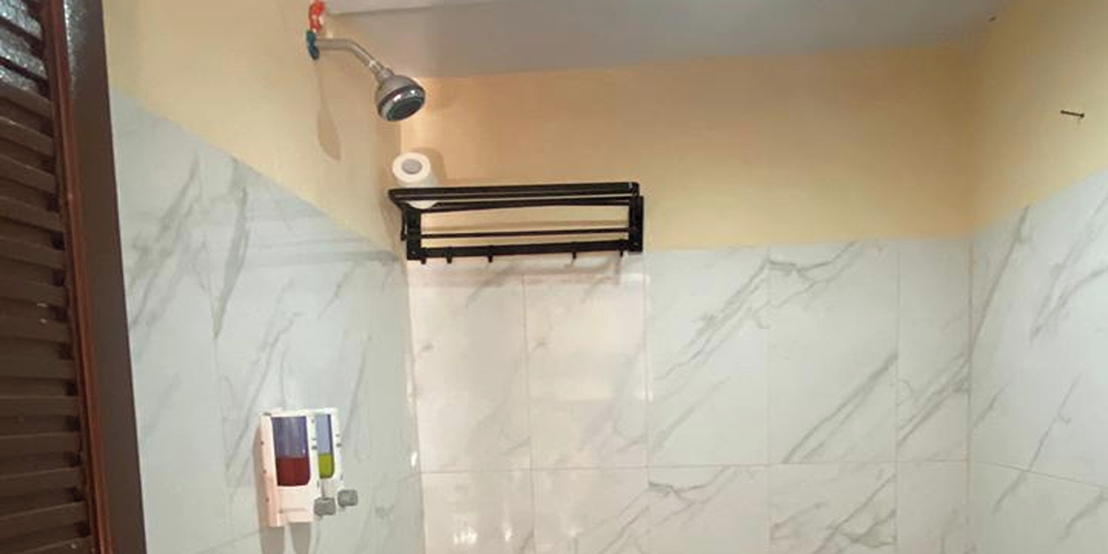 A bathroom with a shower, a towel rack, and a toilet paper holder.