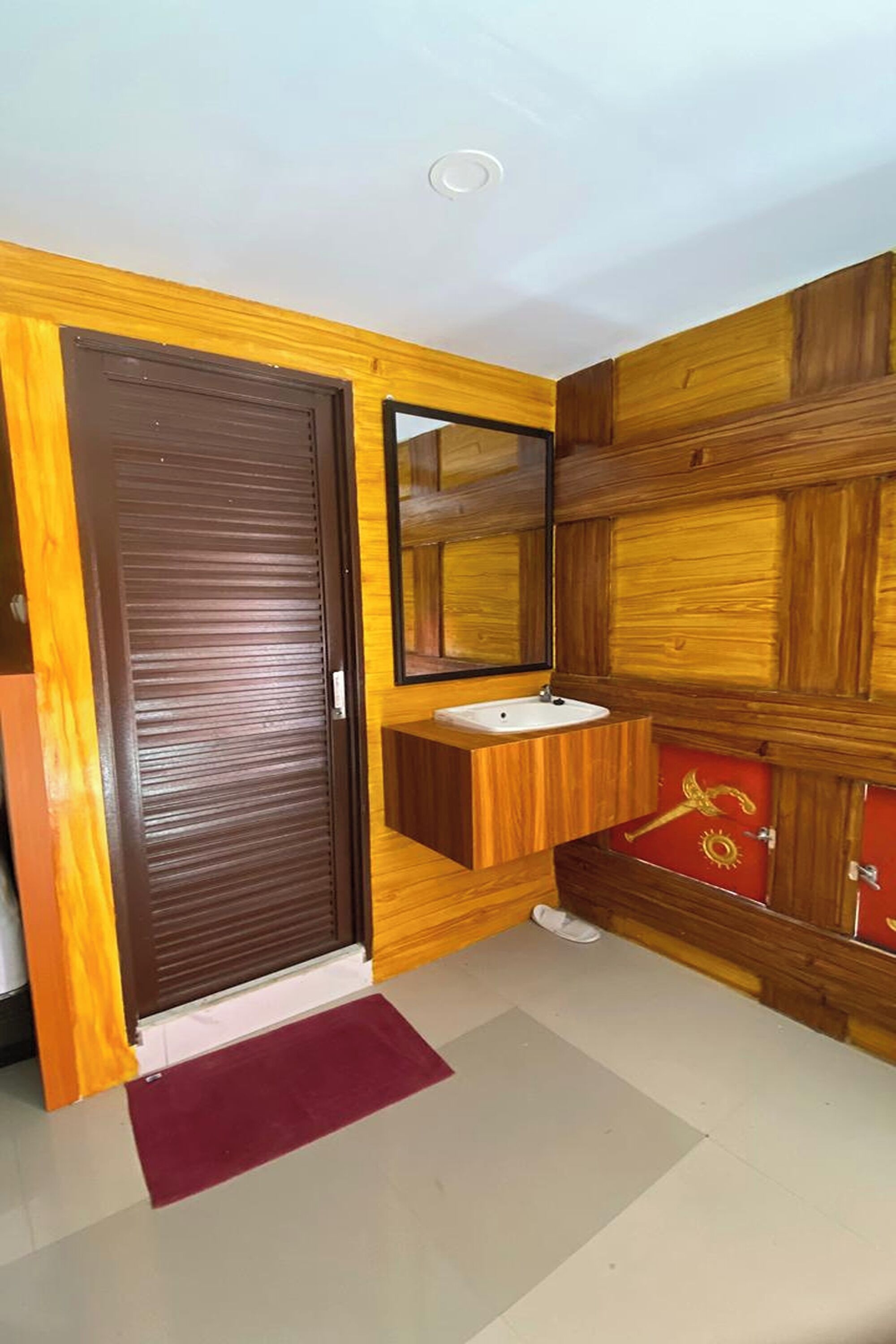 A bathroom with a wooden vanity, a mirror, and a red cabinet with a golden key design.