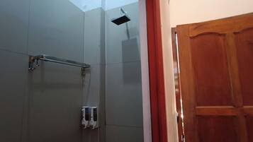 Un baño con cabina de ducha de vidrio, una puerta de madera y un perchero para toallas.