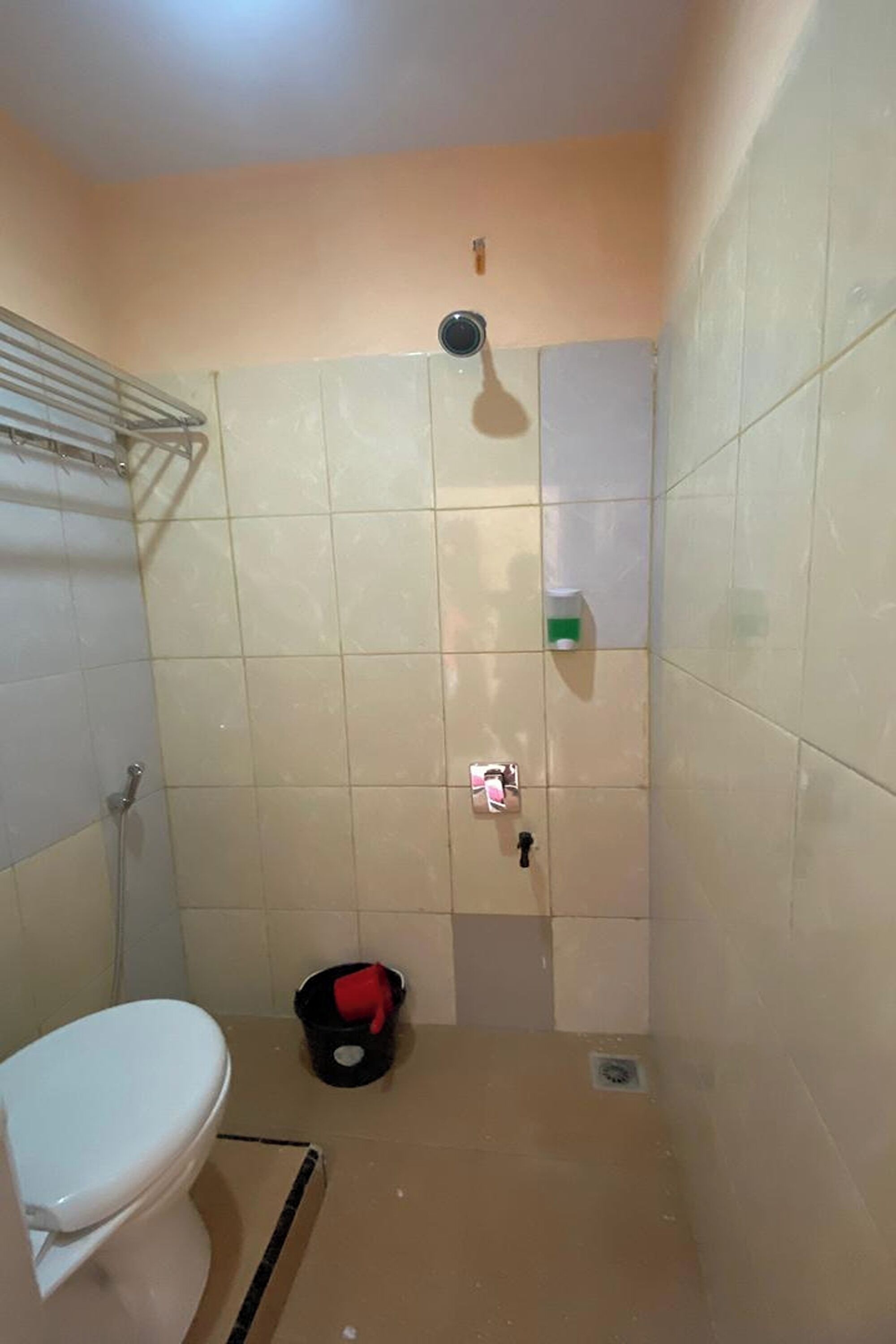 A small, tiled bathroom with a toilet, shower, and a hand dryer.