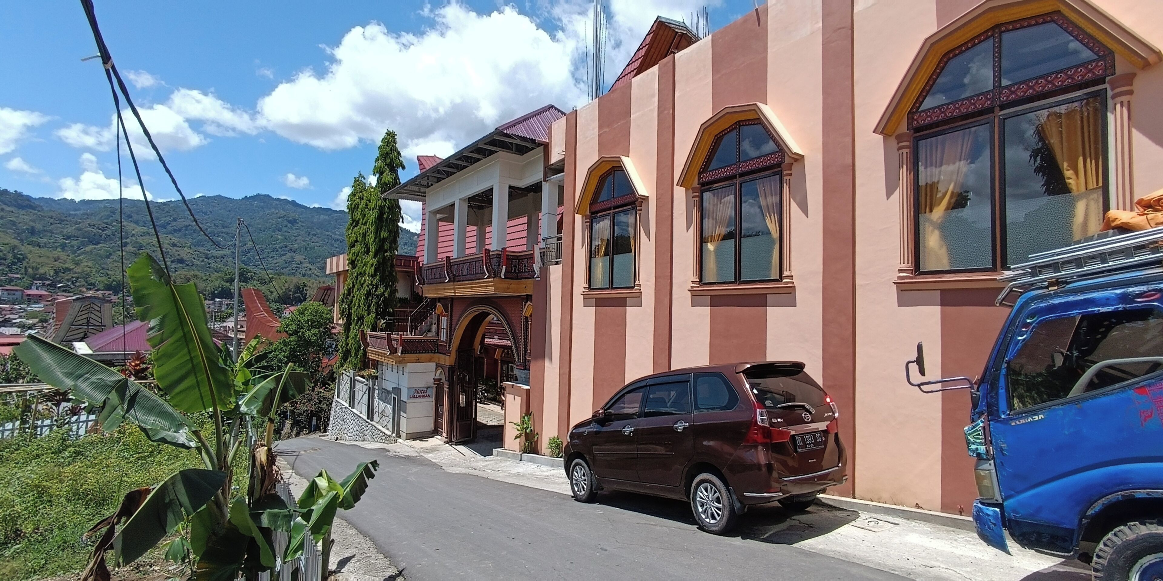 A two-story building with a balcony, a parked car, and a blue truck.