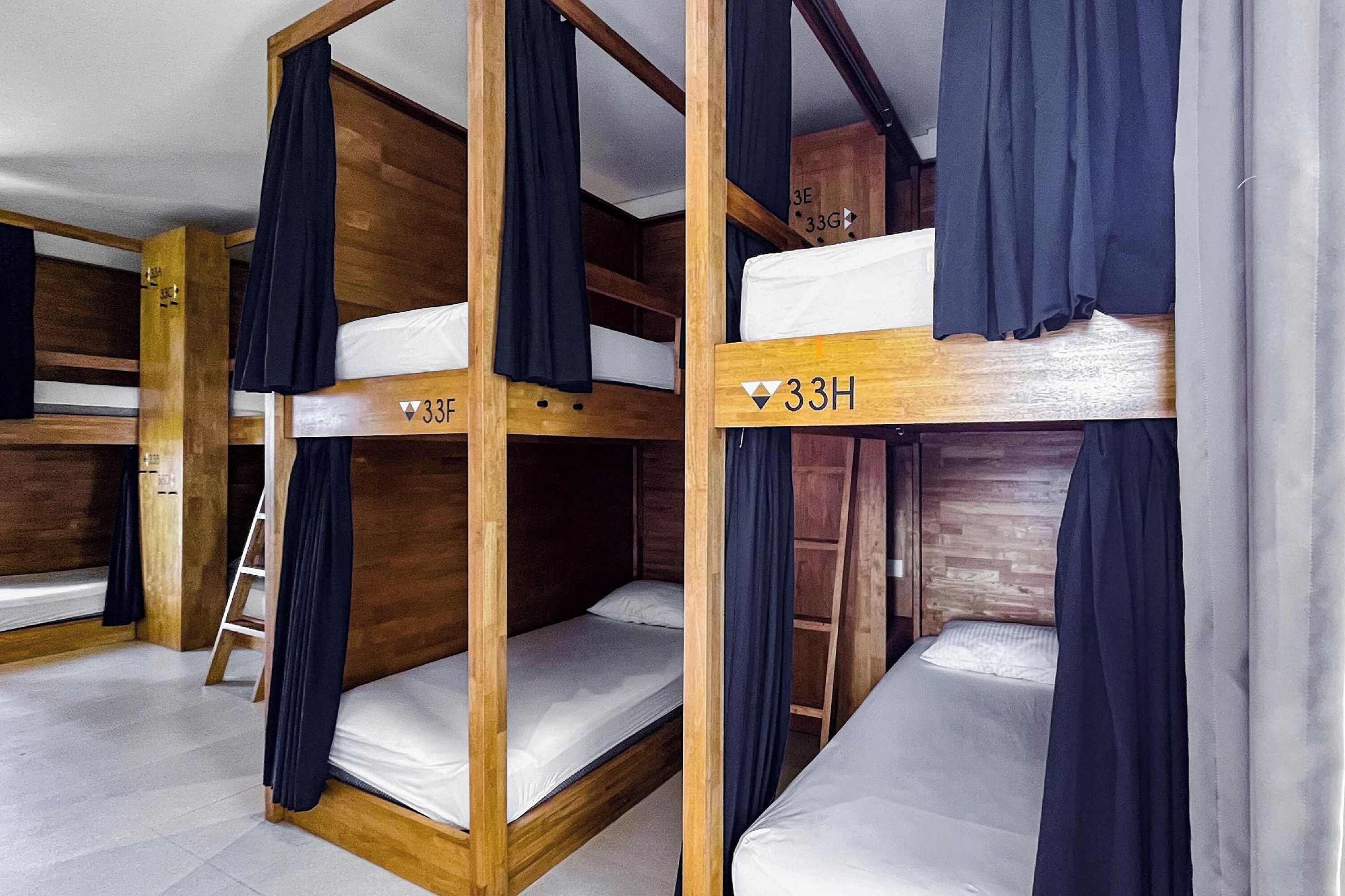 A room with bunk beds, wooden walls, and curtains.