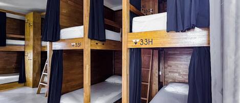 A room with bunk beds, wooden walls, and curtains.