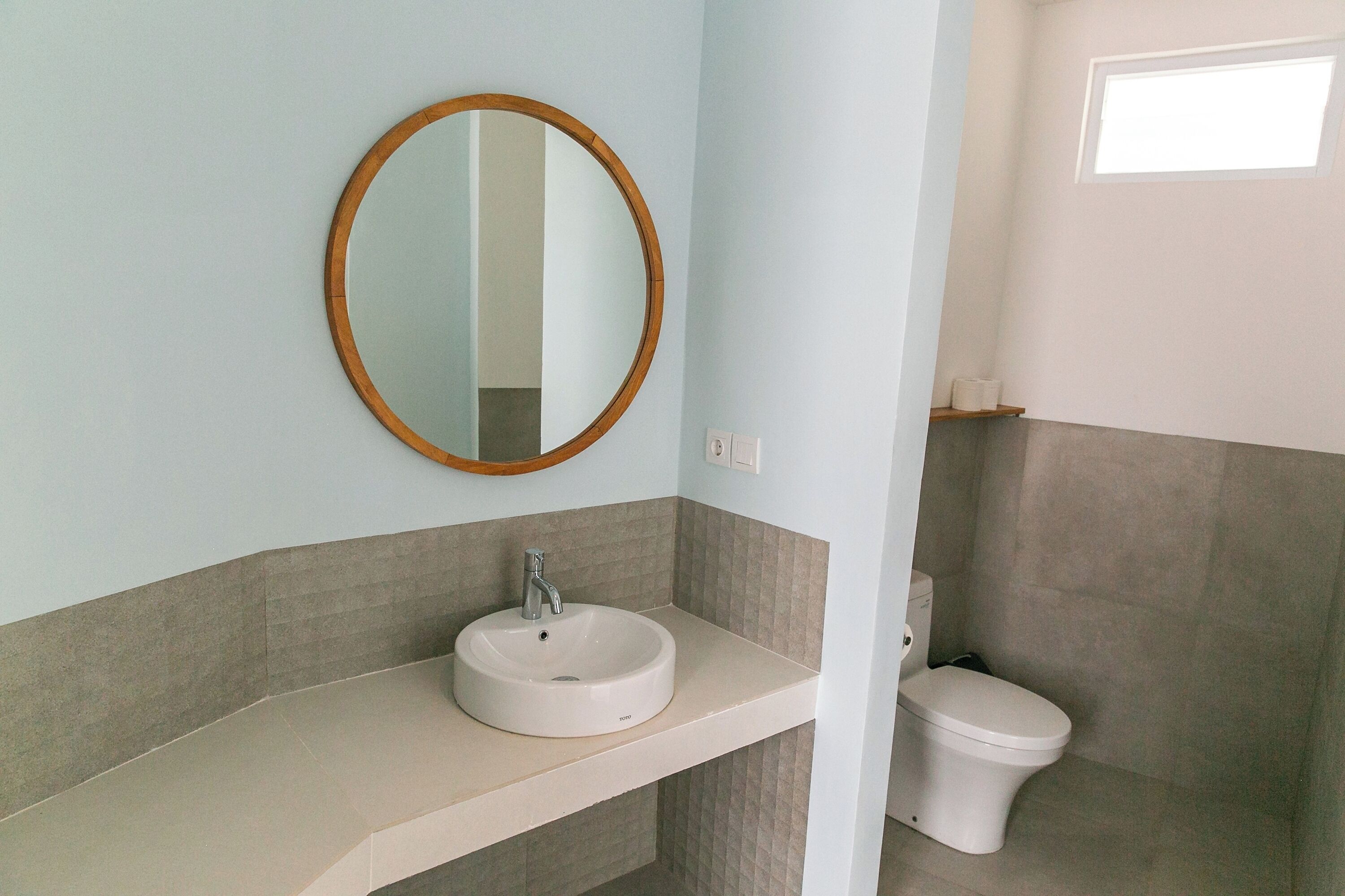 A bathroom with a white sink, a mirror, and a toilet.