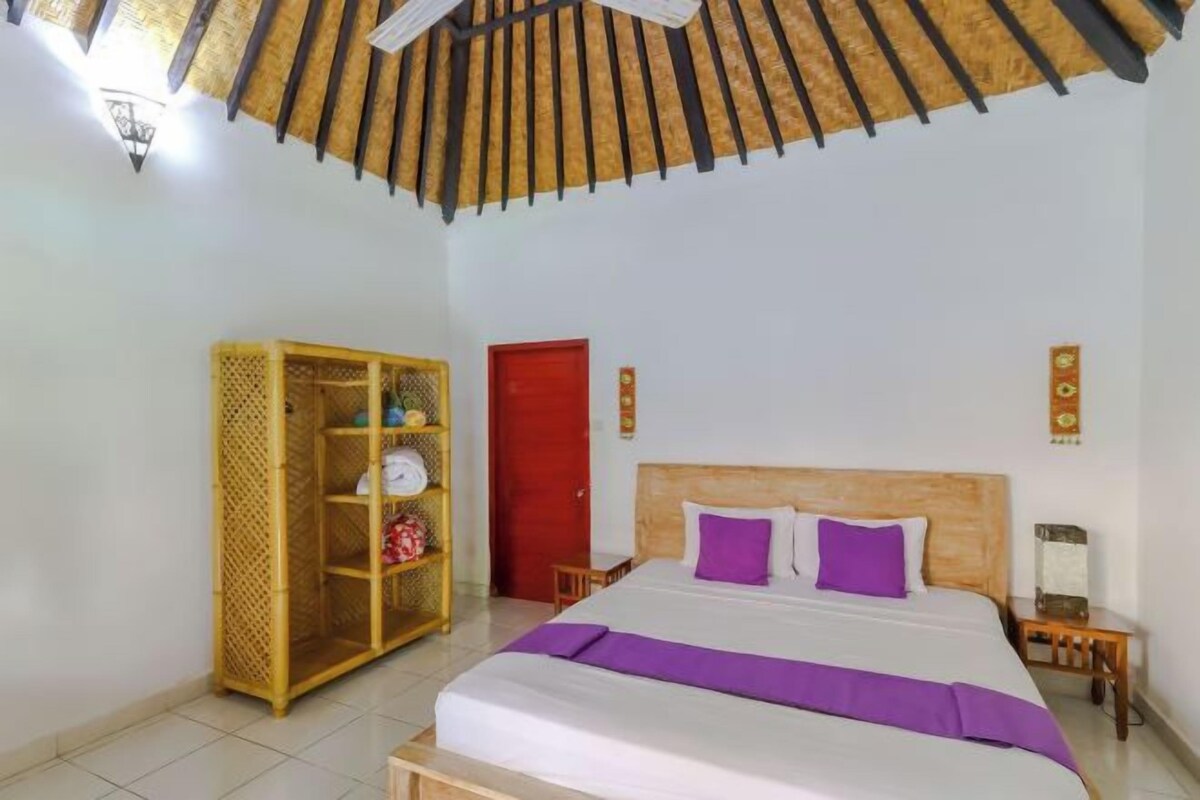 Un dormitorio con cama, armario, una puerta roja y ventilador de techo.
