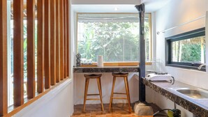 Una cocina compacta con ventana, dos taburetes, un lavabo y una estufa a gas.