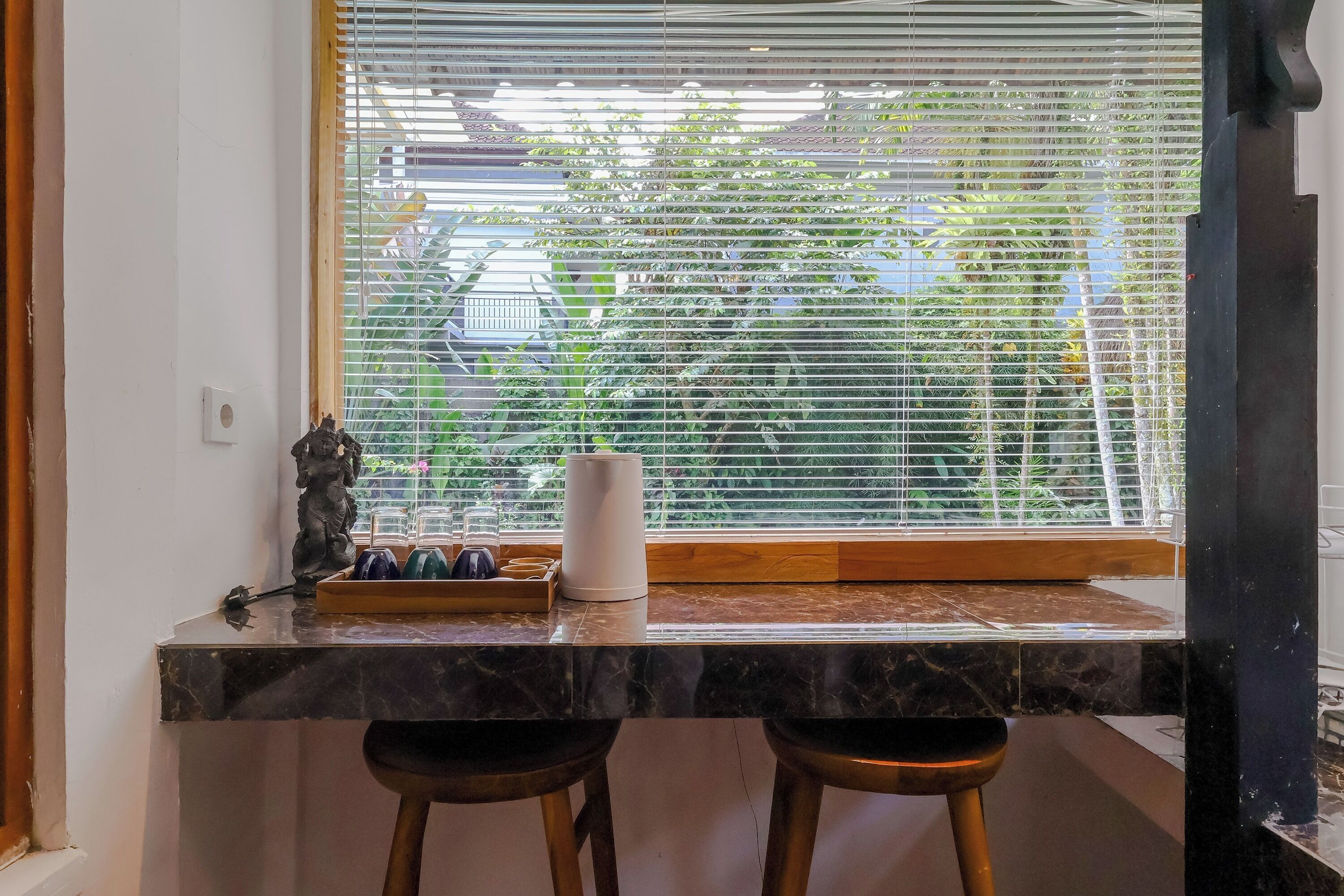 A kitchen counter with a marble top, a white vase, and a small statue.