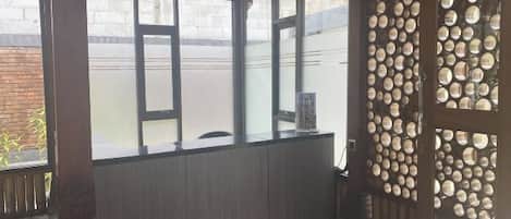A room with a view through a window, a wooden partition, and a wall with circular decorations.