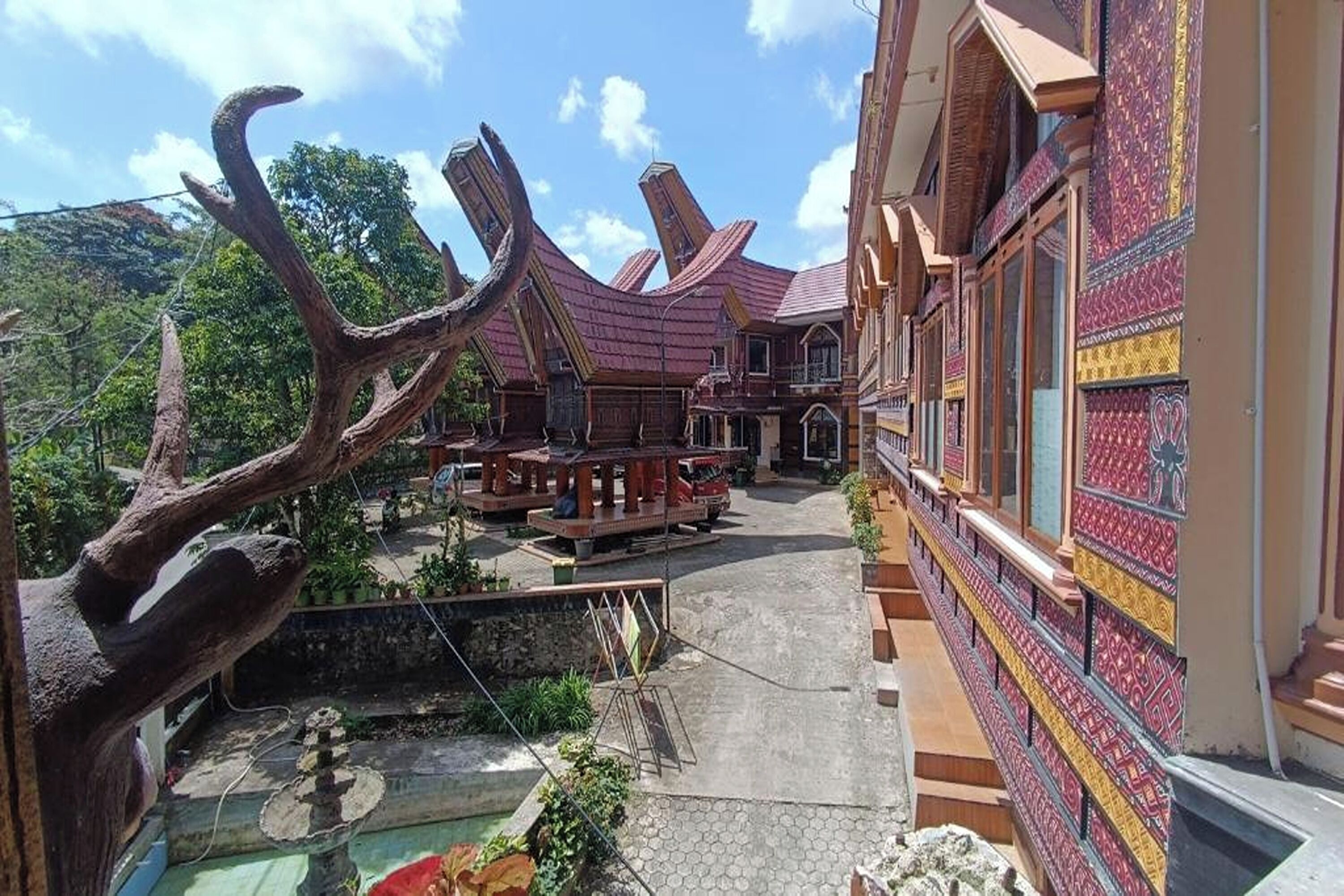 Un edificio tradicional con un patio, bancos de madera y un árbol decorativo.