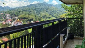 Uma varanda com vista para uma paisagem montanhosa e uma cidade abaixo.