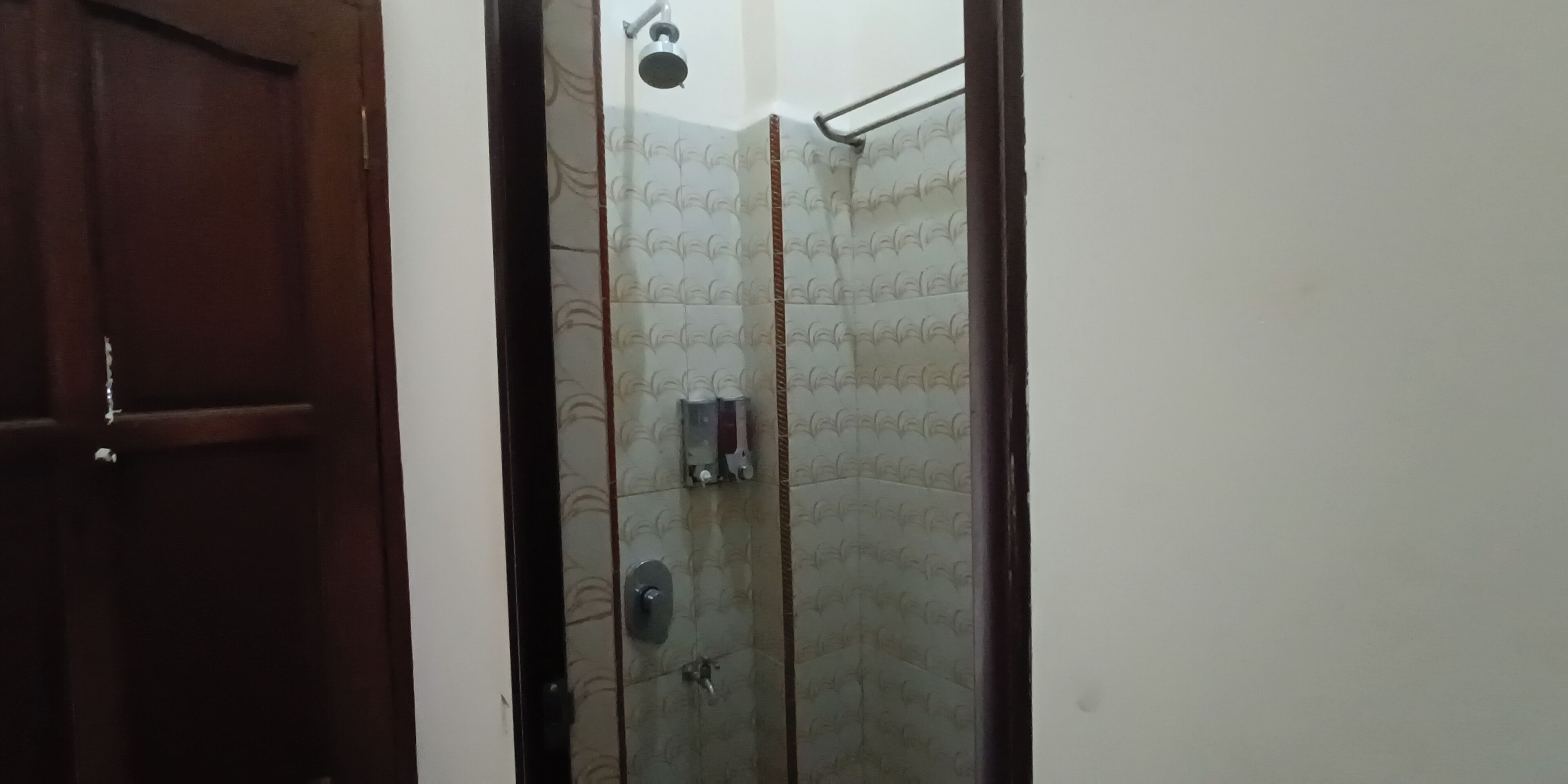 A bathroom with a shower, a towel rack, and a toilet.