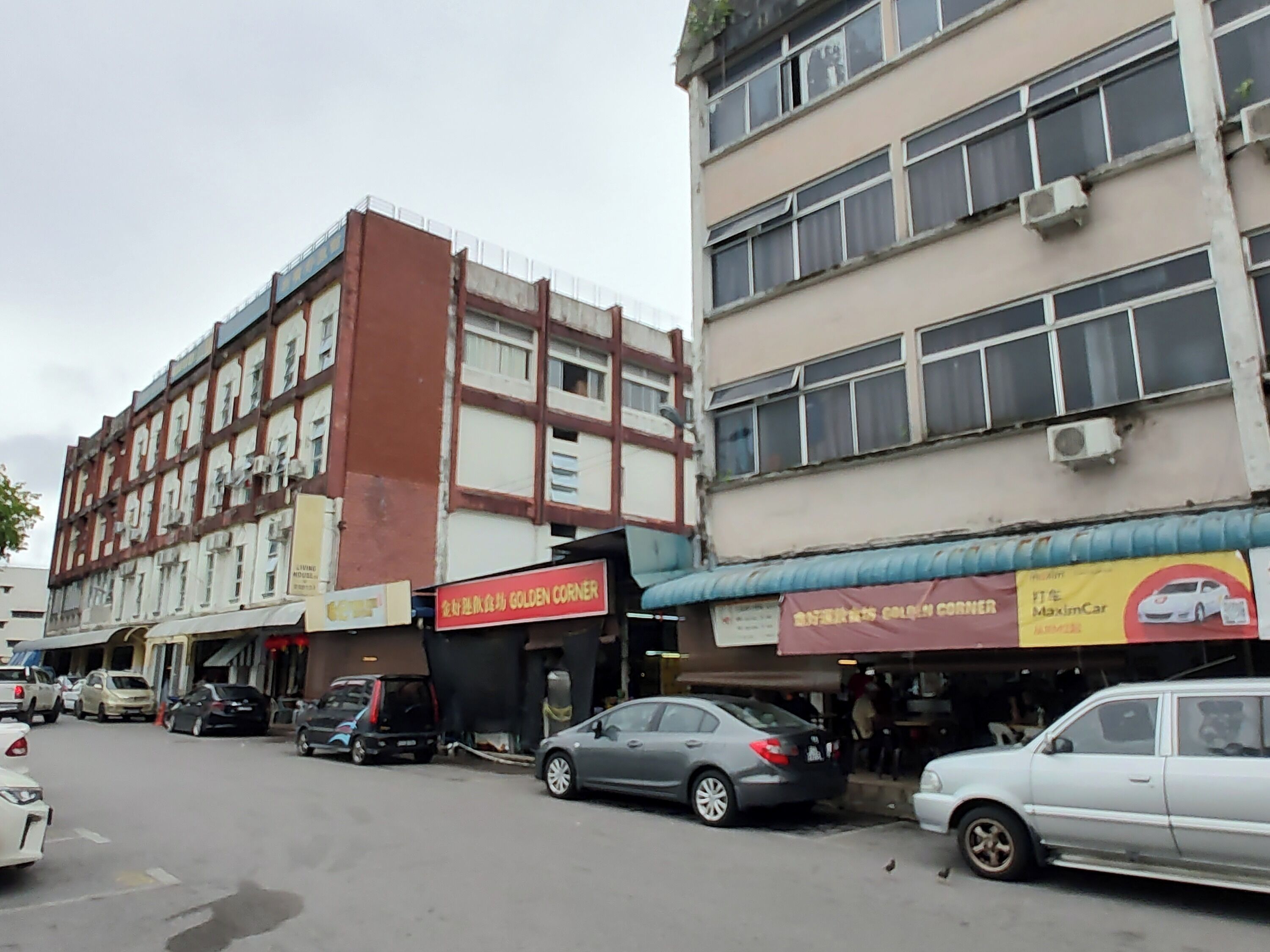 A street view with multiple parked cars and a building with signage for 'Golden Corner'.