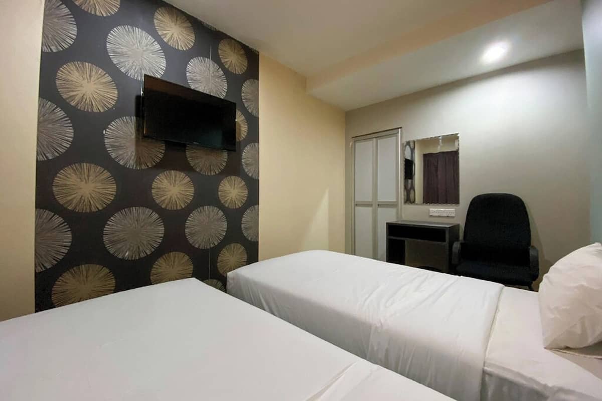 A hotel room with two single beds, a desk with a chair, a flat-screen TV mounted on the wall, and a mirror above the desk.