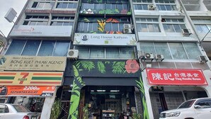 Un edificio de varios pisos con diversos comercios, incluyendo Long House Kailynn y Ting Noodle House.