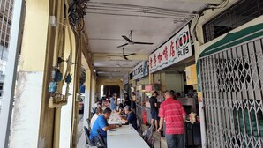 Un restaurante con terraza, ventilador de techo y un cartel que dice '100 PLUS'.