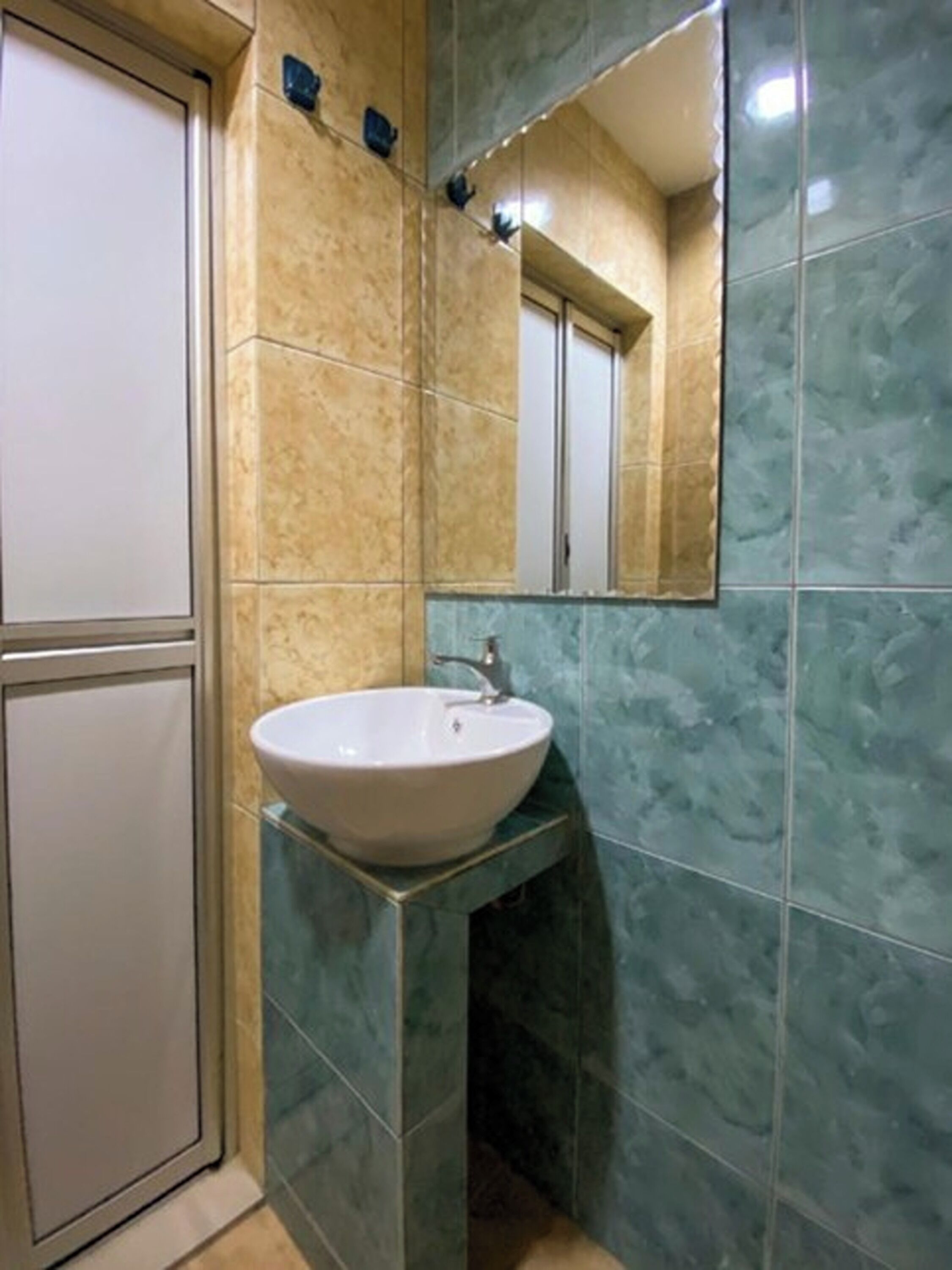 Een badkamer met een witte wastafel, een spiegel en een deur.