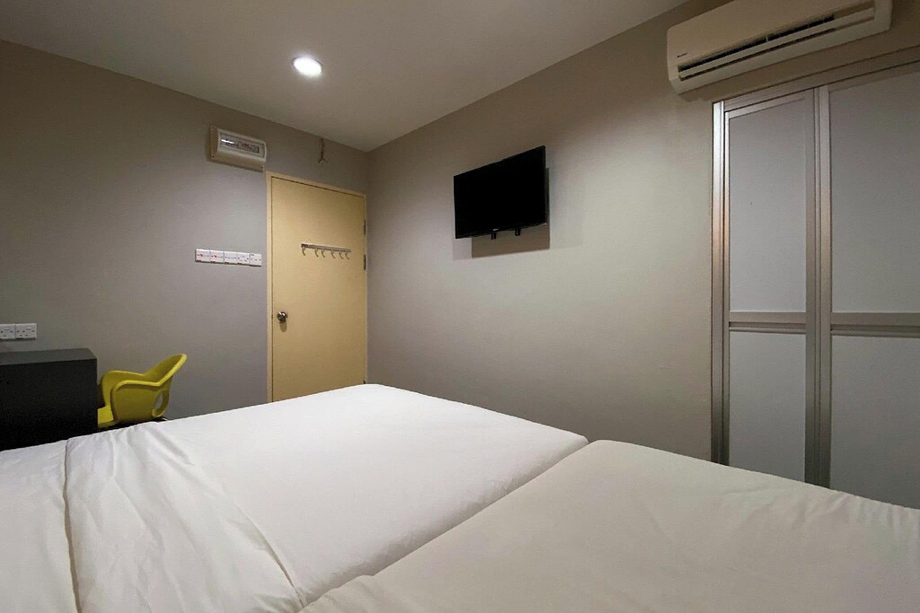 Una habitación de hotel con cama, escritorio, silla, televisión y aire acondicionado.