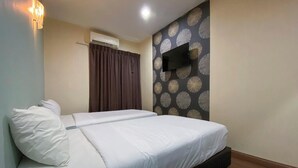 Cama doble con ropa blanca, televisor montado en la pared y un diseño de papel tapiz estampado.