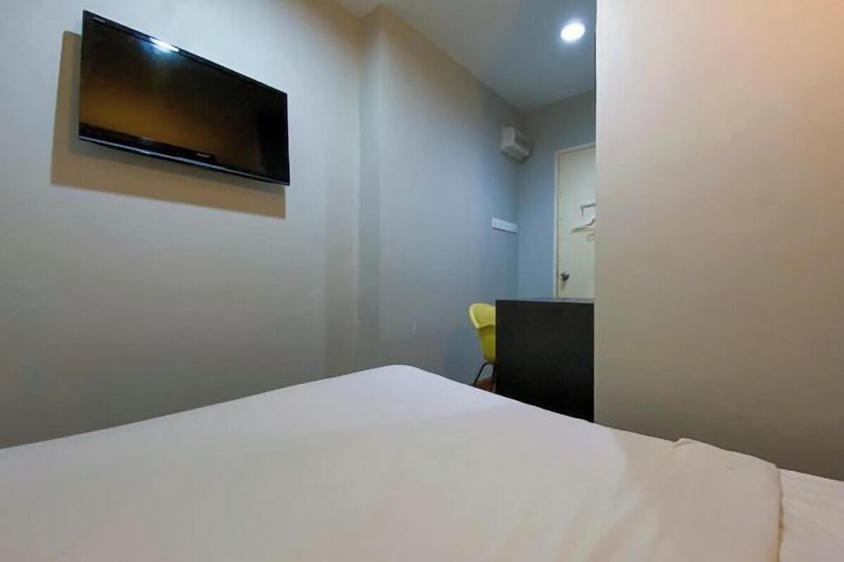 Une chambre d’hôtel équipée d’un lit, d’un téléviseur à écran plat fixé au mur, d’un petit bureau et d’une chaise.