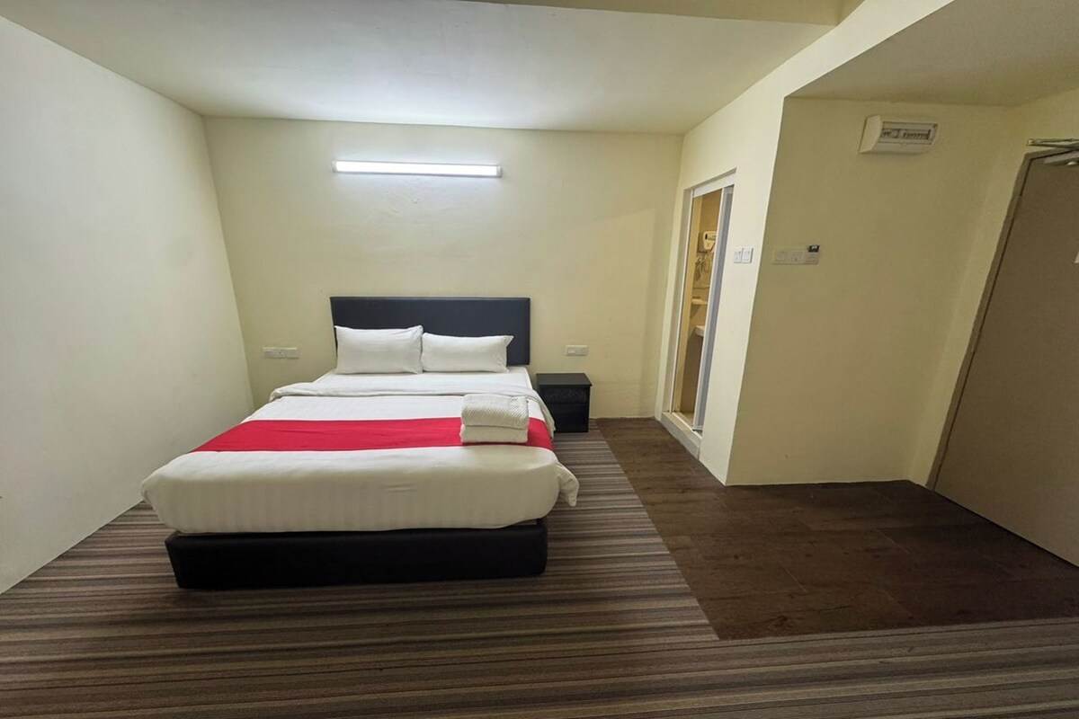 Una habitación de hotel con una cama, una mesita de noche y una ventana.