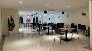 A spacious dining area with multiple tables and chairs, a potted plant, and a wall-mounted sign. - Hotel Seri Warisan Melaka, Stadium Hang Tuah (Malacca City)