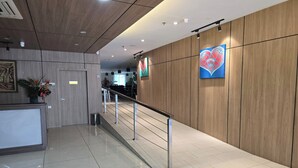 A modern hotel lobby with a wooden reception desk, a staircase with a metal railing, and a wall with a heart-shaped artwork. - Hotel Seri Warisan Melaka, Stadium Hang Tuah (Malacca City)