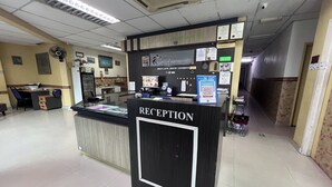 Un mostrador de recepción con un cartel, una computadora y varios carteles informativos.