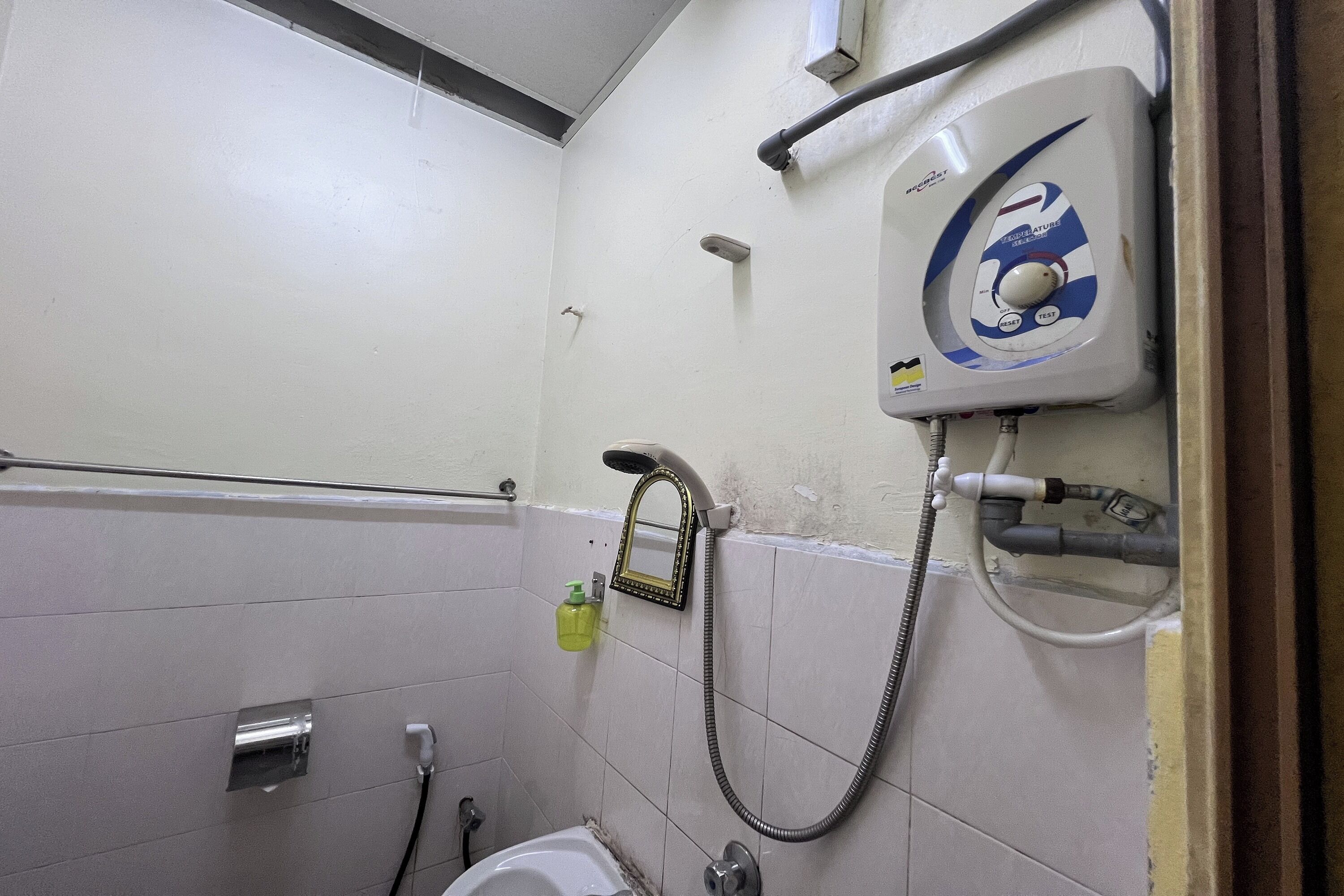 Un baño pequeño con inodoro, ducha y secamanos.