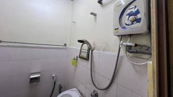 Un baño pequeño con inodoro, ducha y secamanos.
