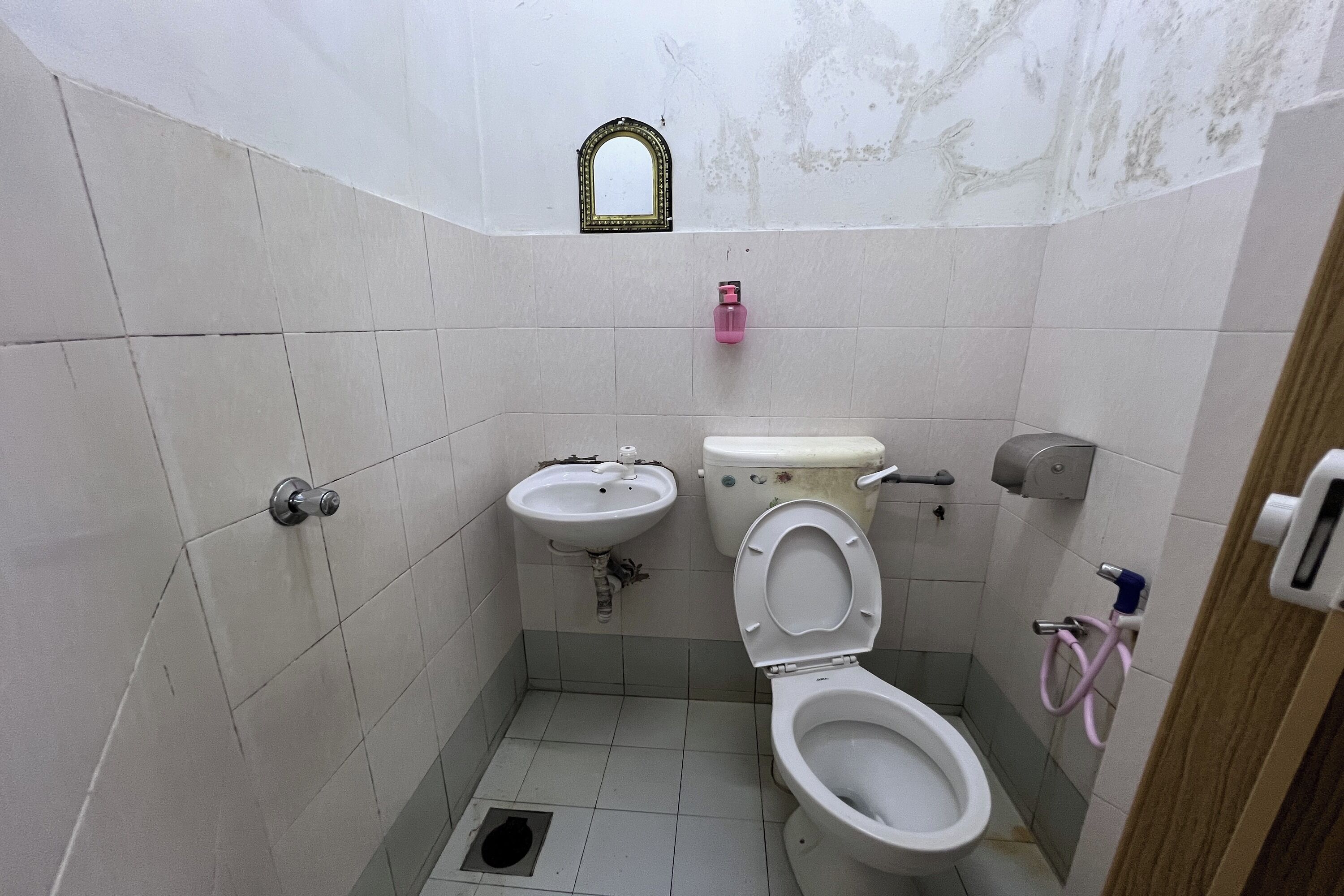 Casa de banho pequena e revestida com mosaicos, com lavatório, sanita e espelho.