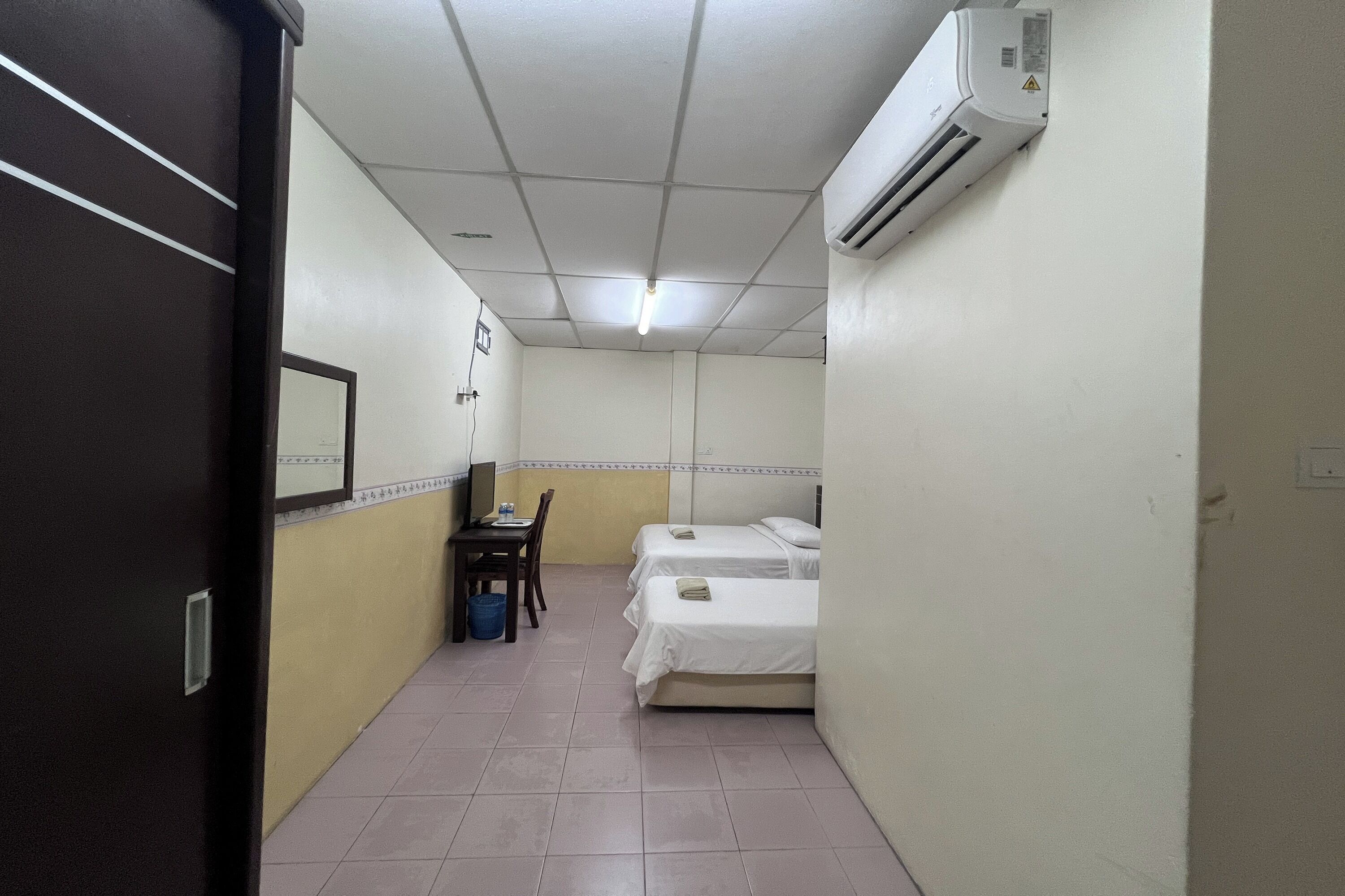 Une chambre d’hôtel avec deux lits, un bureau, une chaise et un appareil de climatisation.