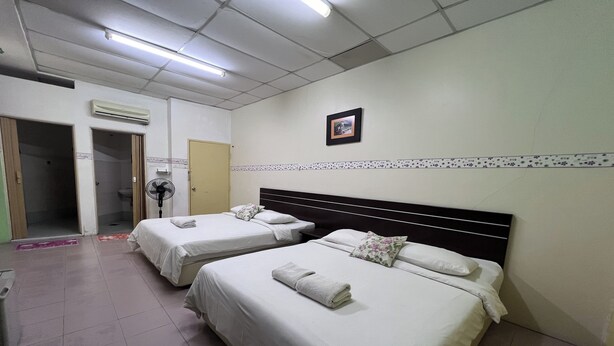 Una habitación de hotel con dos camas, un ventilador, un equipo de aire acondicionado y un cuadro en la pared.
