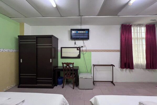 A room with two beds, a desk, a chair, a wardrobe, a television, and a window with curtains. - Seri Kemaman Inn, Chukai Terengganu (Chukai)