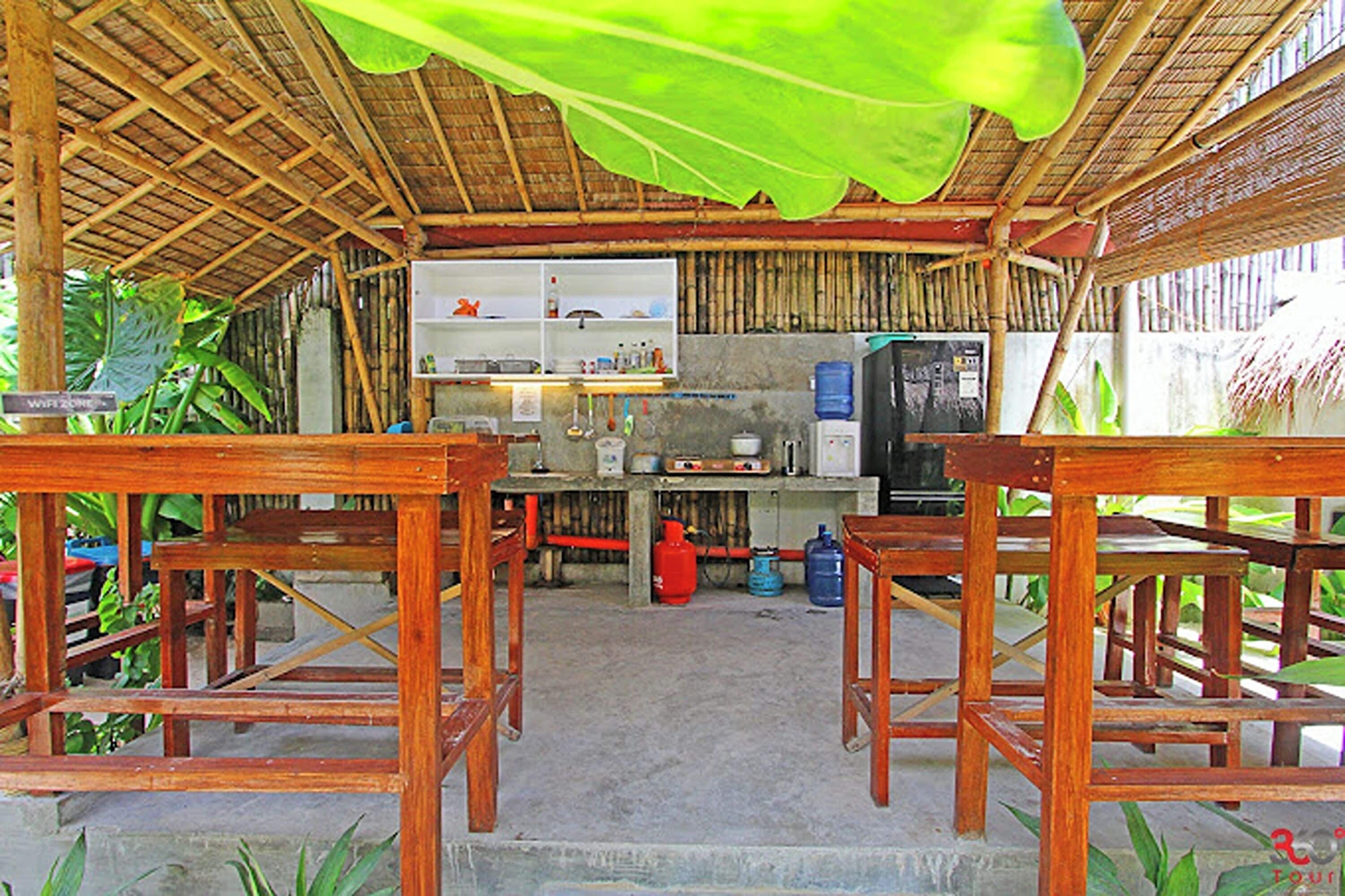 Un espace de cuisine extérieur rustique, avec des tables en bois et un toit de chaume.