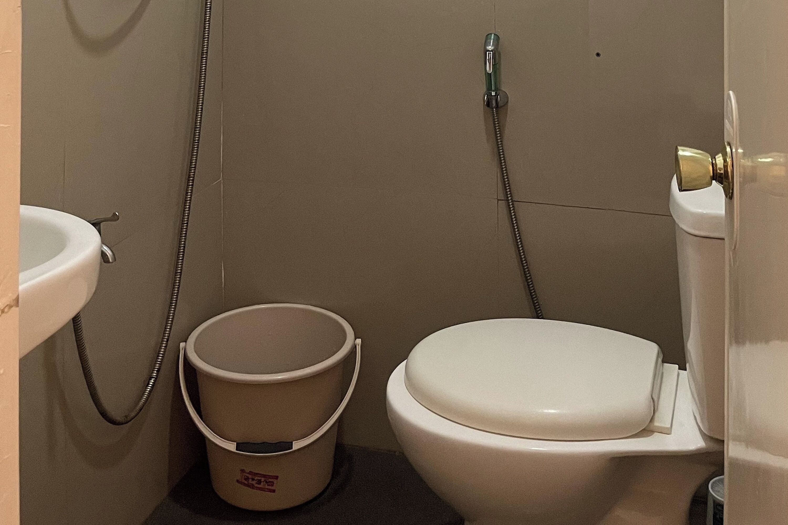 Un baño con inodoro, lavabo y un balde.