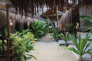 A pathway lined with potted plants and a thatched roof structure. - Mazawa Siargao (General Luna)