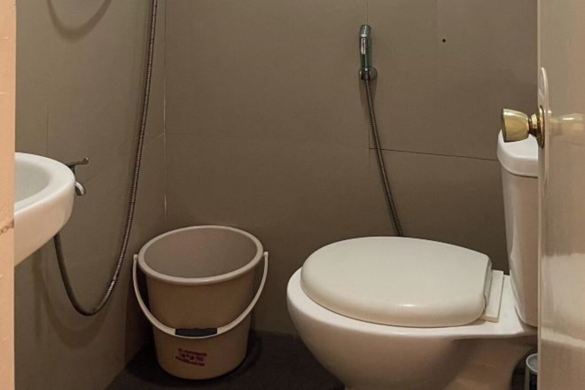 A bathroom with a toilet, a sink, and a bucket.