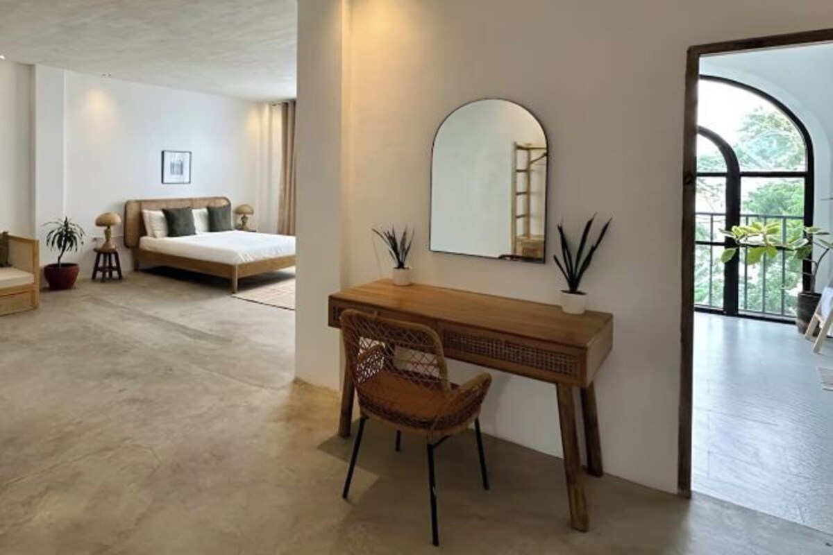 A modern bedroom with a wooden desk, a large mirror, and a view of the outdoors.