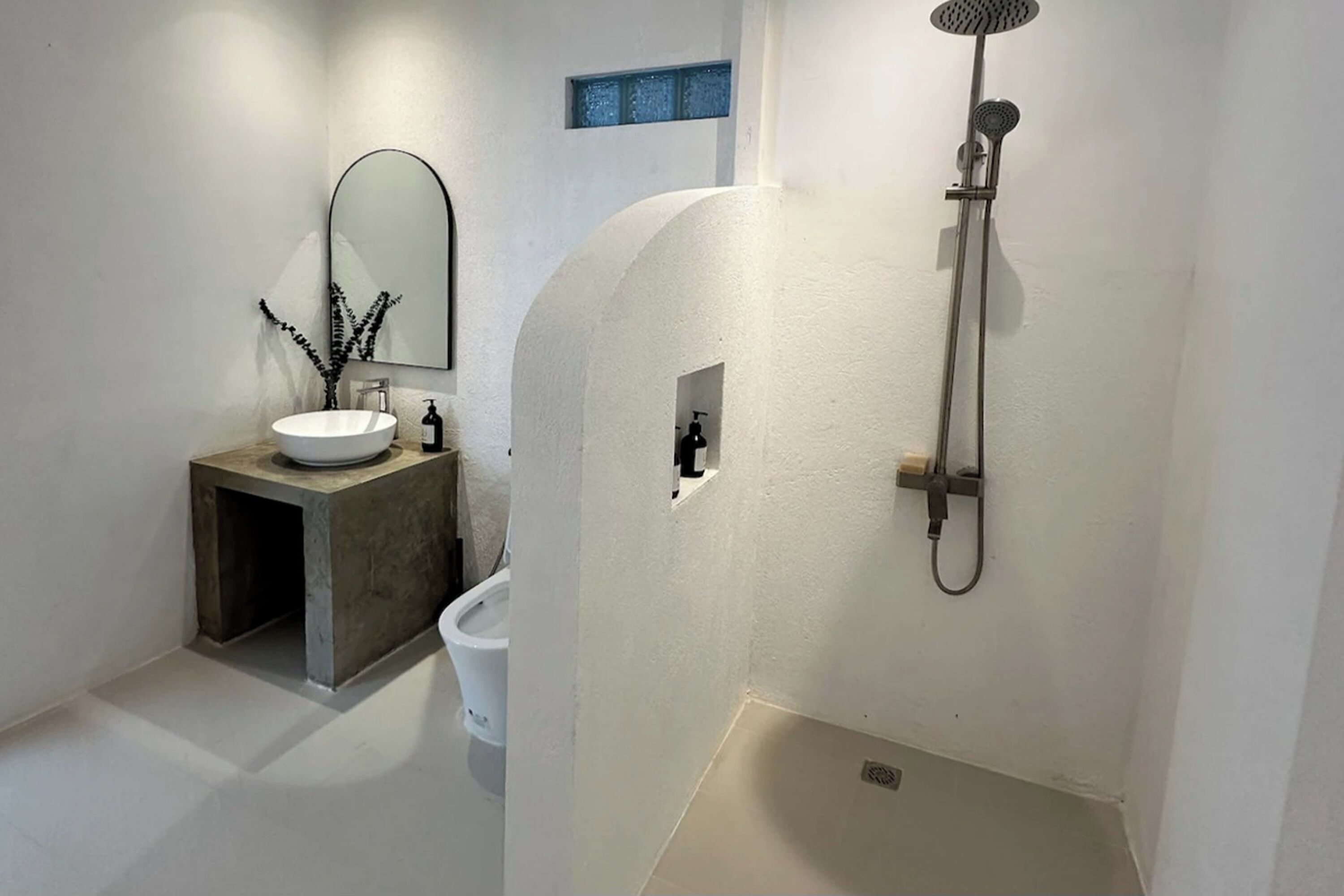 Un baño moderno con un lavabo blanco, un espejo y una ducha.