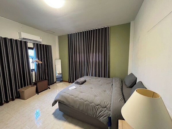 Habitación de hotel con cama, lámpara de noche, espejo, armario y ventana con cortinas.