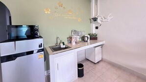 Una cocina compacta equipada con microondas, lavamanos y una pequeña encimera.