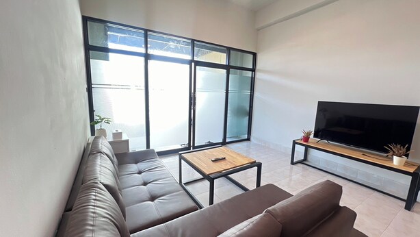 Una sala de estar moderna con un conjunto de sofás, una mesa de centro y un televisor sobre un mueble.