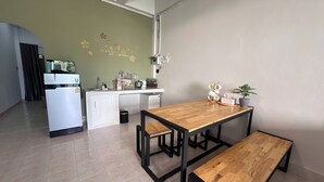 Una cocina compacta con comedor, que incluye una mesa de madera y bancos, un refrigerador blanco y una pequeña isla con electrodomésticos.