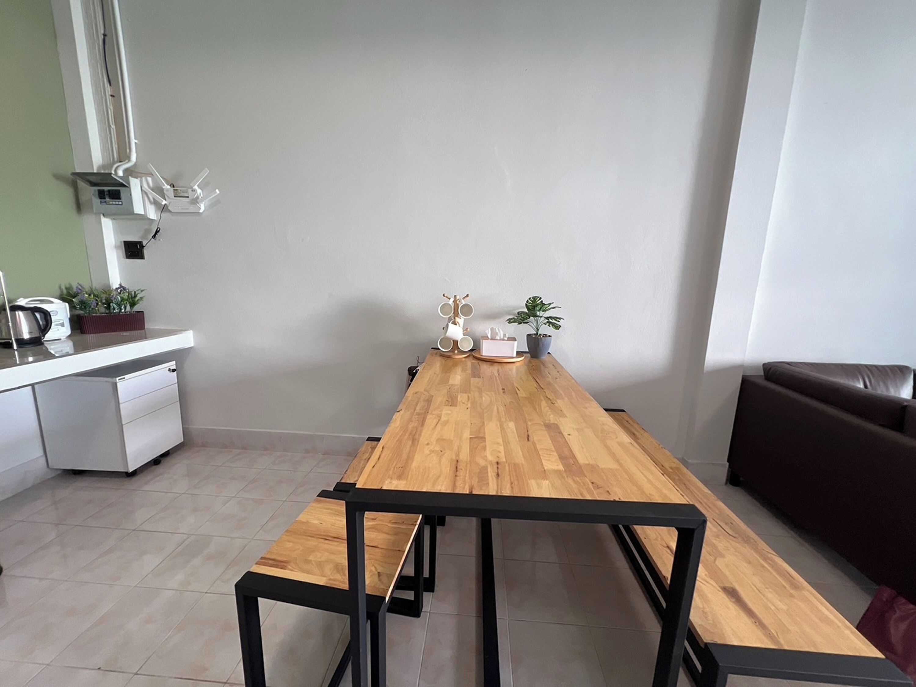Una cocina moderna con una mesa de madera, una encimera blanca y un sofá de cuero marrón.