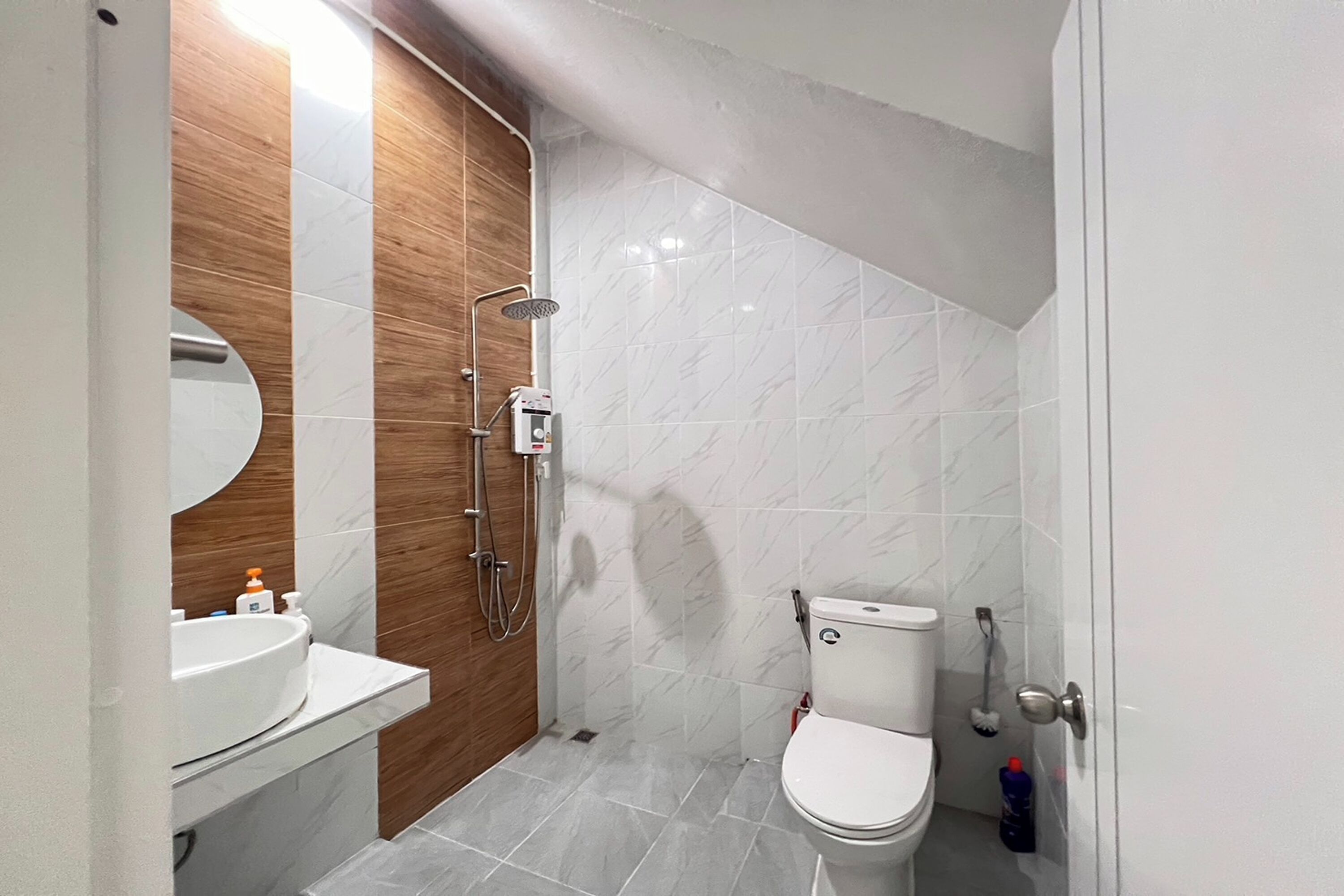 A modern bathroom with a wooden vanity, a toilet, and a shower.