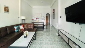 A modern living room with a brown leather sofa, a marble coffee table, and a flat-screen TV mounted on the wall. - Kuan Mapraw Villa 2 (Phatthalung)